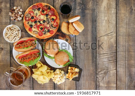 Fast food on old wooden background. Concept of junk eating. Top view. Flat lay. Royalty-Free Stock Photo #1936817971