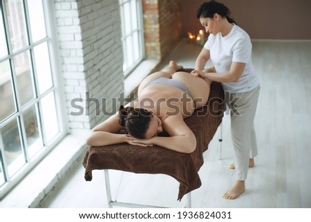 The masseur is giving massage to a fat woman. Spa massage for correction figure. Treatment massage for weight loss in spa salon. High quality photo.