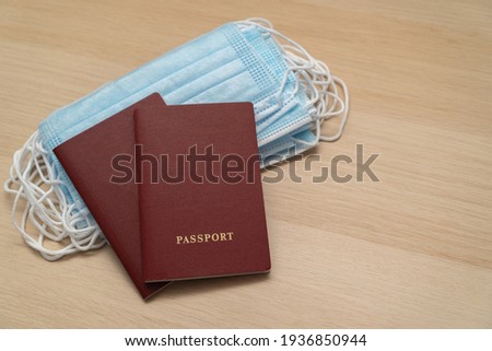 A pair of passports lie on a pack of medical masks on a wooden table. Stop traveling to dangerous places to prevent coronavirus