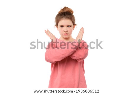 Stop. Serious-looking determined teen girl making stop sign with crossed hands, saying no, expressing security, defense or restriction, isolated over white background