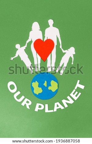 Earth Day. A felt-cut symbol of the planet earth and a red heart with paper silhouette of family. Green background with text. Flat lay. Vertical. The concept of environmental protection.
