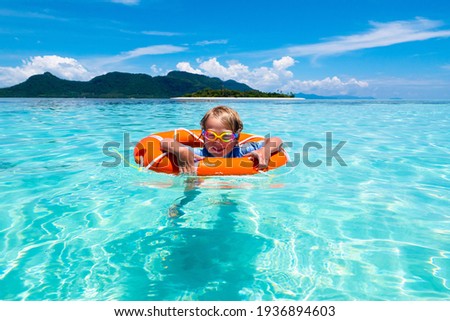 Child with inflatable ring on beautiful beach. Little boy swimming in exotic sea. Ocean vacation with kid. Children play on summer beach. Water fun. Kids swim. Family holiday on tropical island.