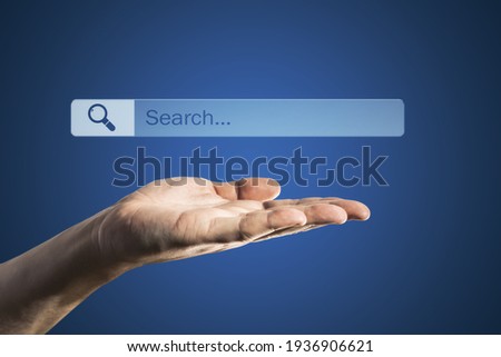 Online search concept with search box with magnifier icon over man hand on blue background