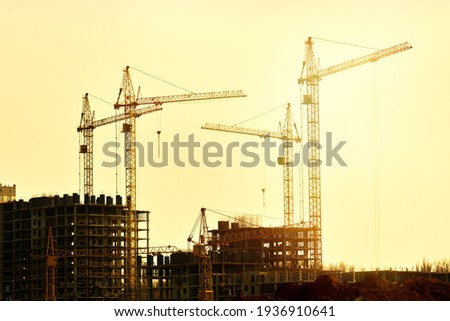 Construction of new residential high-rise buildings. Against the background of a yellow sunset sky. Royalty-Free Stock Photo #1936910641
