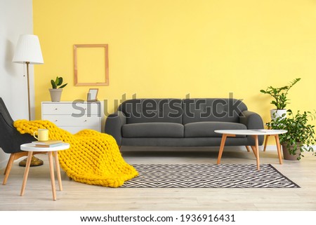 Interior of modern room with sofa, armchair and knitted plaid Royalty-Free Stock Photo #1936916431
