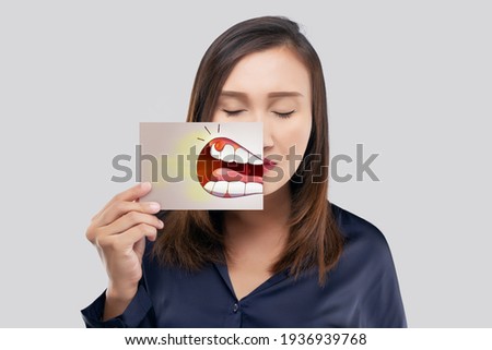 Asian woman in the dark blue shirt holding a paper with the broken tooth cartoon picture of his mouth against the gray background, Decayed tooth, The concept with healthcare gums and teeth Royalty-Free Stock Photo #1936939768