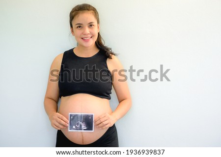 Asian pregnant woman show with ultrasound baby on white background.