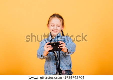A little cute girl making photo on a yellow background.