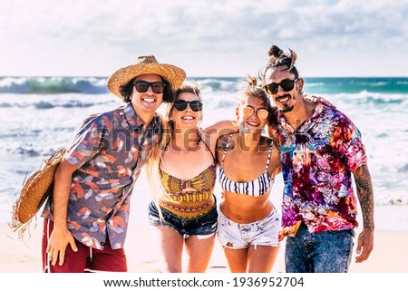 Group of young people friends have fun and enjoy friendship at the beach in summer holiday vacation smiling and laughing - blue ocean and sky background - beach lifestyle youthful people outdoor