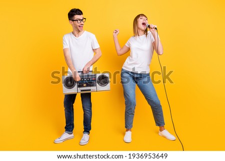 Photo of funky persons dressed white t-shirt glasses showing listening boom box singing microphone isolated yellow color background