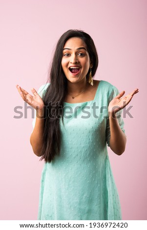 Pretty Indian asian young woman or girl presenting against pink background Royalty-Free Stock Photo #1936972420