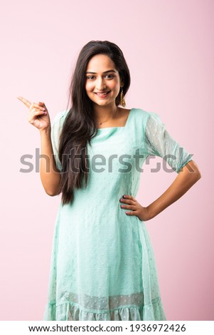 Pretty Indian asian young woman or girl presenting against pink background