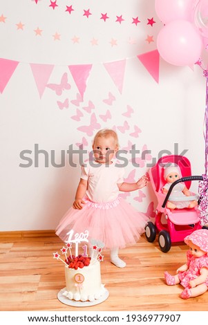 photo shoot of a little girl in a pink curvy skirt for her birthday in one year. baby and cream cake