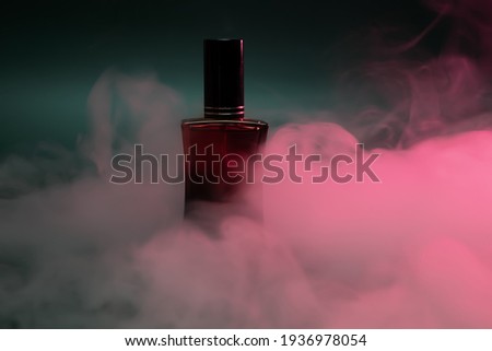perfume in a red bottle on a dark green background with steam. High quality photo