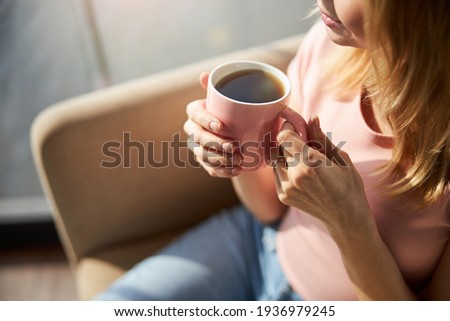 Young woman holding pink cup of coffee Royalty-Free Stock Photo #1936979245
