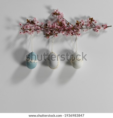 Happy easter composition. Elegant decorated easter eggs hanging from a branch of spring pink flowers.
