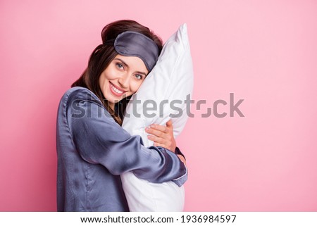 Photo portrait of woman hugging pillow isolated on pastel pink colored background with blank space