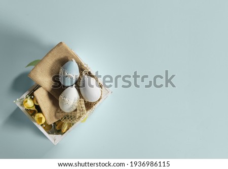 Photo composition for Easter. Eggs decorated in a wooden box with light blue background.
