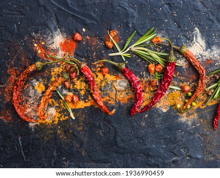 Spicy red dried chilis with ground spices on black stone background. top view