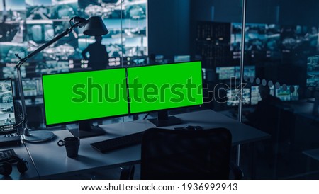 Two Digital Computer Screens with a Green Mock Up Chromakey in Modern Monitoring Office. Control Room with Specialists and Managers Sit in Front of Computers.
