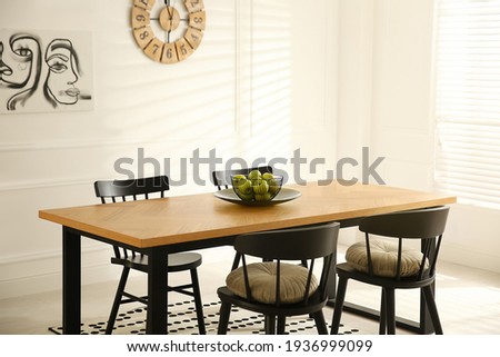 Stylish wooden dining table and chairs in room. Interior design Royalty-Free Stock Photo #1936999099