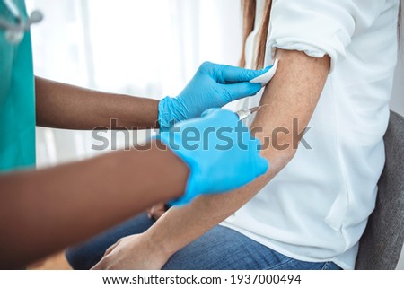 Hands with protective gloves fills syringe with vaccine. Hands of doctor in medical gloves injecting vaccine to a patient. Doctor giving muscular injection to woman. Vaccination healthcare concept.