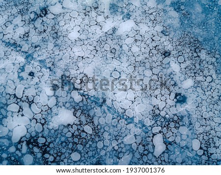 Methane gas bubbles, frozen in the ice surface texture. Lake Baikal winter background