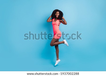 Full length body size photo of happy girl touching hairdo jumping high smiling isolated on vivid blue color background