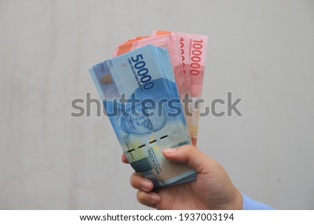woman's hand showing rupiah banknotes on white background. IDR 100000  and IDR 50000 Royalty-Free Stock Photo #1937003194