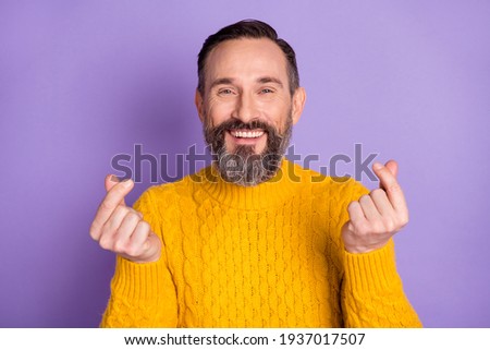 Photo of handsome bearded man show fingers money symbol wear yellow sweater isolated violet background