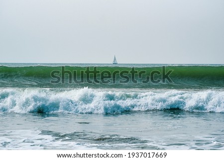 Sea landscape, ocean waves with a yacht in the background, selective focus.
