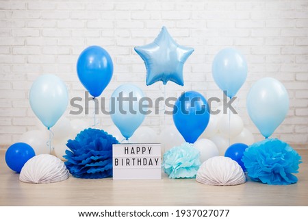 birthday party decoration - air balloons, paper balls and lightbox with happy birtday text over white brick wall