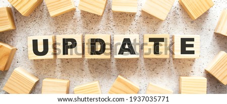 The word UPDATE consists of wooden cubes with letters, top view on a light background. Work space.