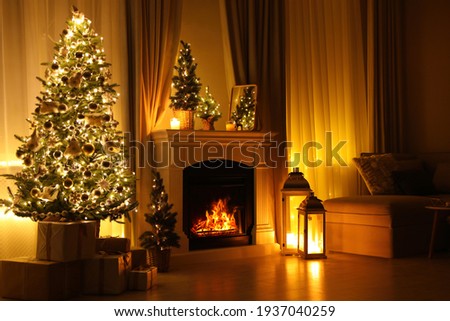Stylish living room interior with beautiful fireplace, Christmas tree and other decorations at night
