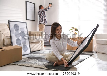 Happy couple decorating room with pictures together. Interior design