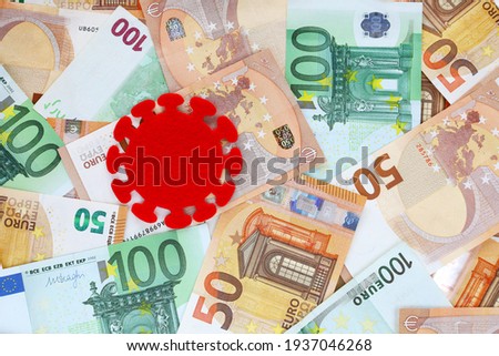 Covid virus symbol cut out of red felt on 50 and 100 euro banknotes background. Coronavirus pandemic in Europe. Financial crisis, bank, money, economy, business concept. Place for text.