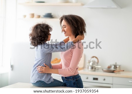 African American daughter hugging her smiling mum