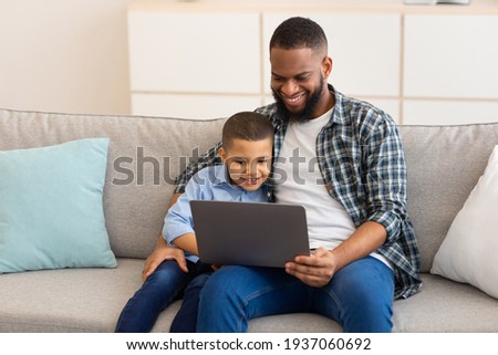 African Daddy And Son Watching Cartoons On Laptop At Home