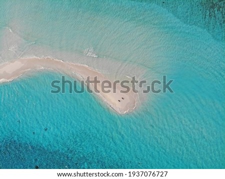 Aerial photo of couple laying on sandbank with turquoise water. Drone picture of two people on white sand on lonely island, Maldives, Indian Ocean. Isolation in tropical paradise.