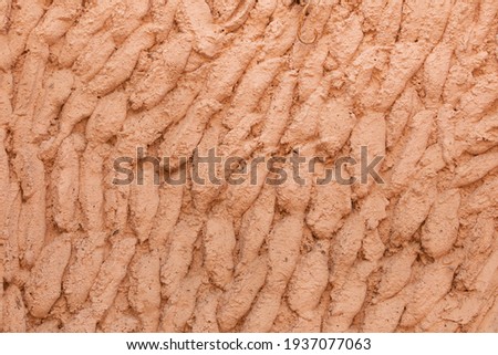 Photography of texture and background of a facade arranged with cement and painted salmon pink, in a house in Ambel, a small town in the Campo de Borja region, Zaragoza, Aragon, Spain.