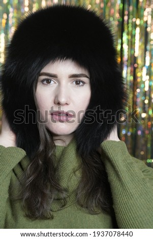 Portrait of casual style woman in winter fur hat close-up, face and hands on glittering background