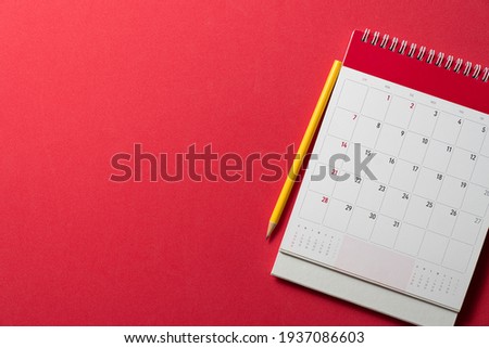 close up of calendar and yellow pencil on the red table background, planning for business meeting or travel planning concept