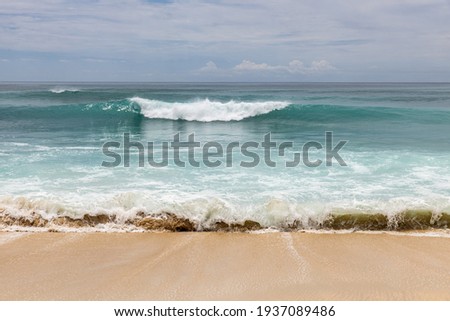 Seascape background. Sandy beach, milky foam waves, blue ocean. Scenic waterscape. Horizon line. Cloudy sky. Nature and environment concept. Daylight. Copy space. Dreamland beach, Bali, Indonesia