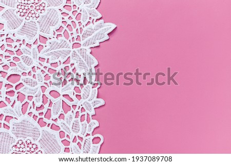 Beautiful white lace cloth on pink background, close up. Copy space. Text place. White lace floral textile fashion pattern. Openwork fabric white lace texture Royalty-Free Stock Photo #1937089708