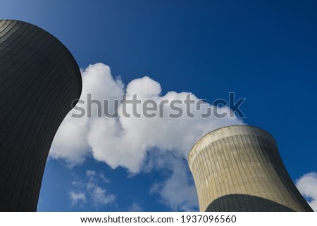 Low angle view on cooling towers with water steam on a blue sky, nuclear plant Royalty-Free Stock Photo #1937096560