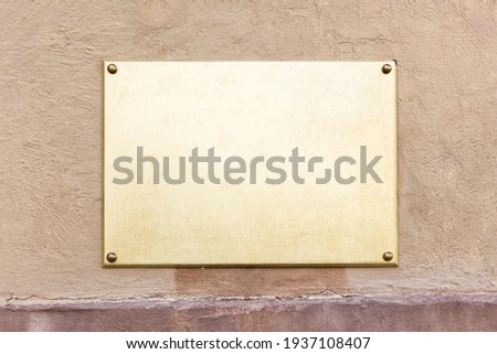 Mockup template golden metallic information board on aged brown colored wall.