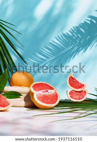 Fresh healthy grapefruit on sunlight with hard shadows. Minimal food creative concept on blue pastel background. Grapefruit slices citrus fruits. Royalty-Free Stock Photo #1937116510