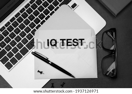 Paper with words IQ Test in envelope, glasses and laptop on black table, flat lay