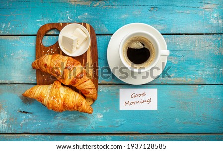 Fresh croissants and black coffee isolated on blue wooden background. Top view.