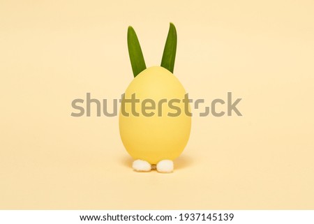 Easter egg with bunny ears on a yellow background. Flat lay.